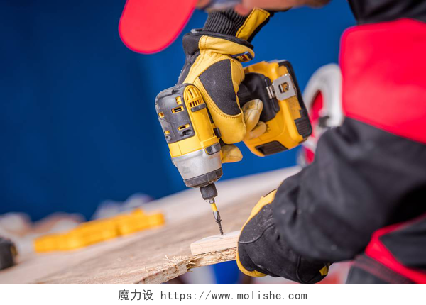 一个工人拿着电钻在钻木头建筑工人用钻具驱动木工。电动工具设备.